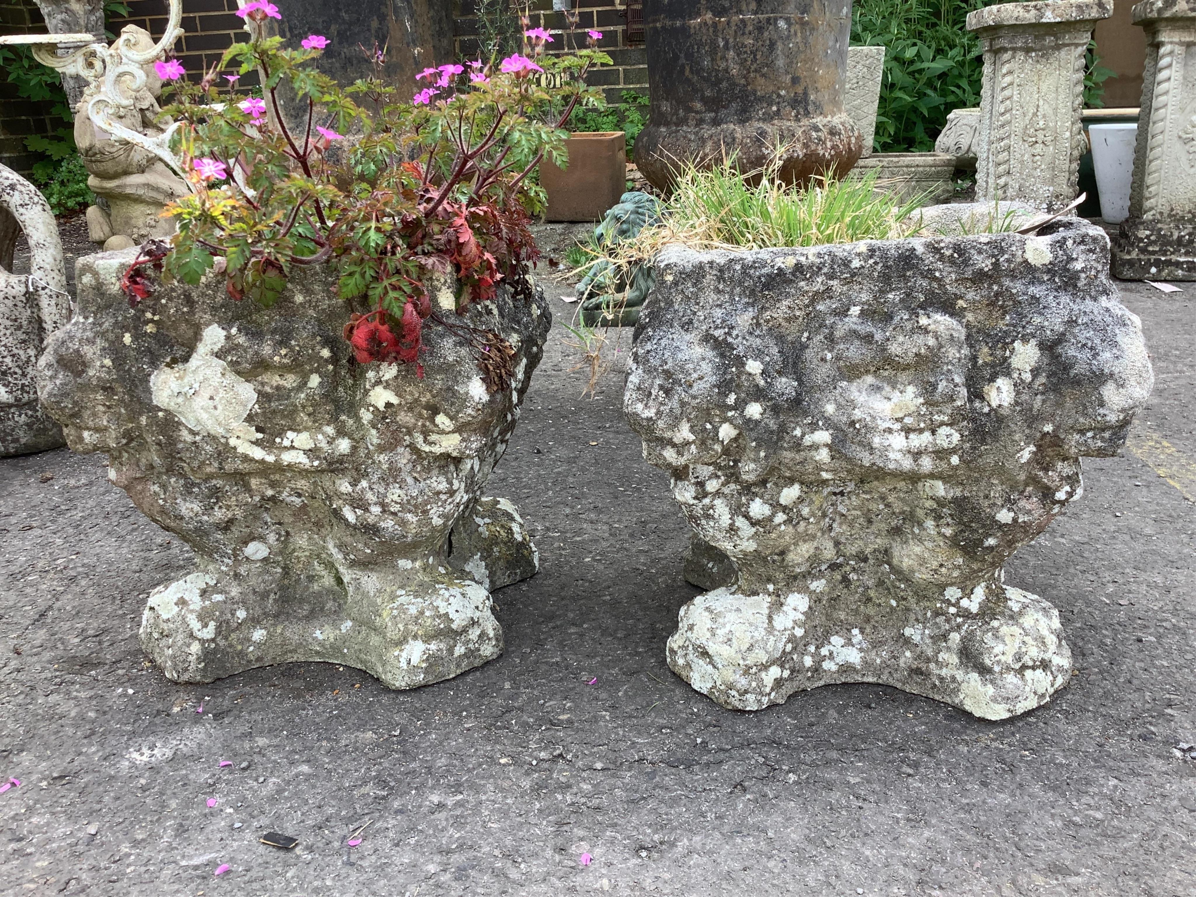 A pair of small reconstituted stone garden urns, moulded with lion masks, width 30cm, height 33cm